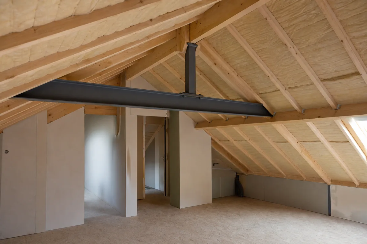 Comble de maison en charpente mixte, poutre métallique peinte portant des chevrons en bois clair