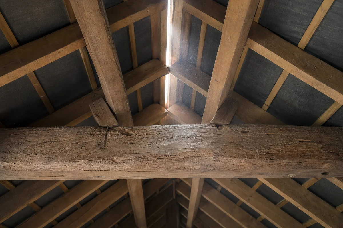 Combles vus de l&rsquo;intérieur avec la panne faîtière et la sous-face de la couverture éclairée par la lumière du jour