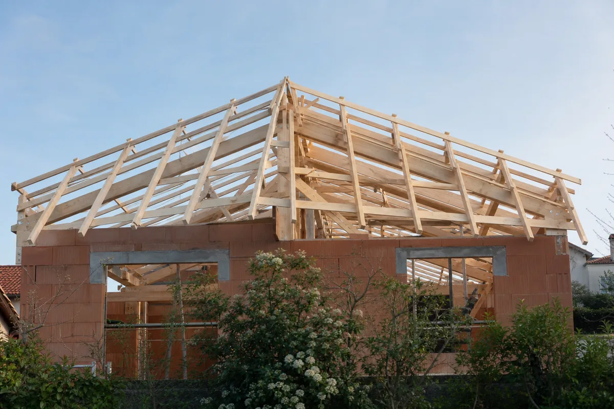 Maison individuelle en cours de surélévation avec charpente neuve montée sur des murs d’étage